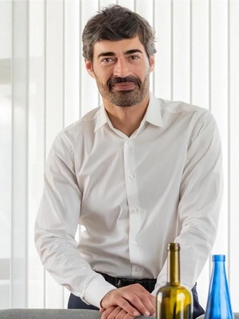 Raúl Gómez, consejero delegado (CEO) de Vidrala, apoyado en una mesa con botellas de vidrio de varios colores