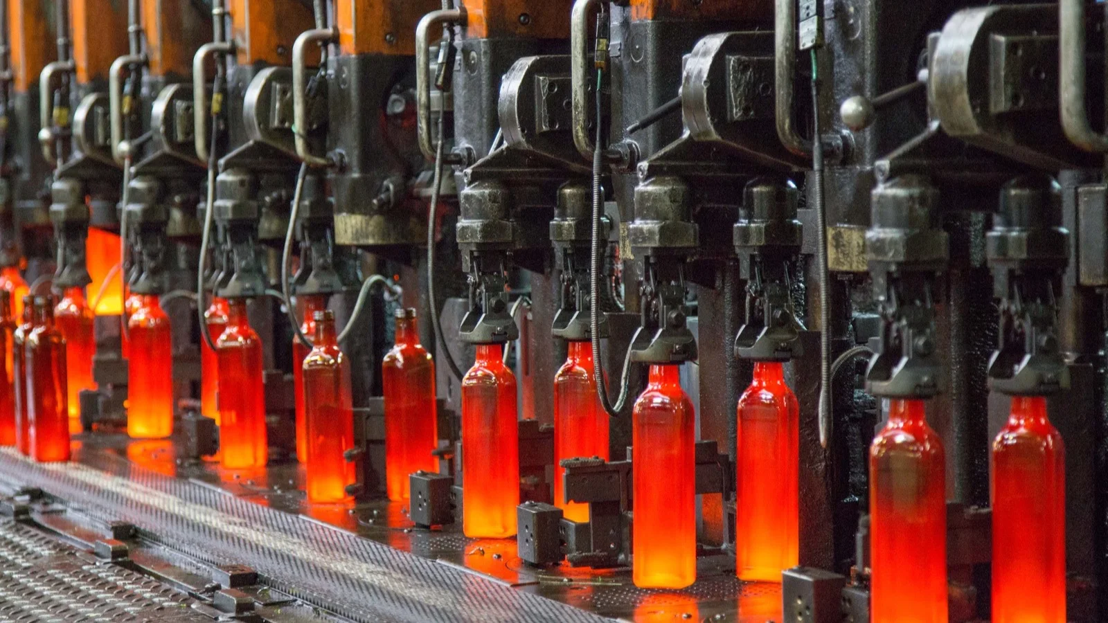 Botellas de vidrio al rojo saliendo de la máquina formadora en una fábrica de Vidrala
